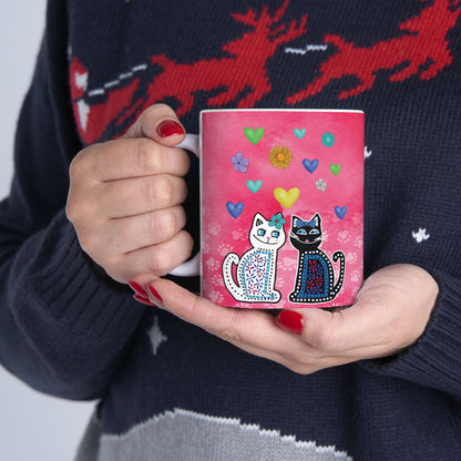 Mug with two cats and colorful hearts and flowers design on a pink background.