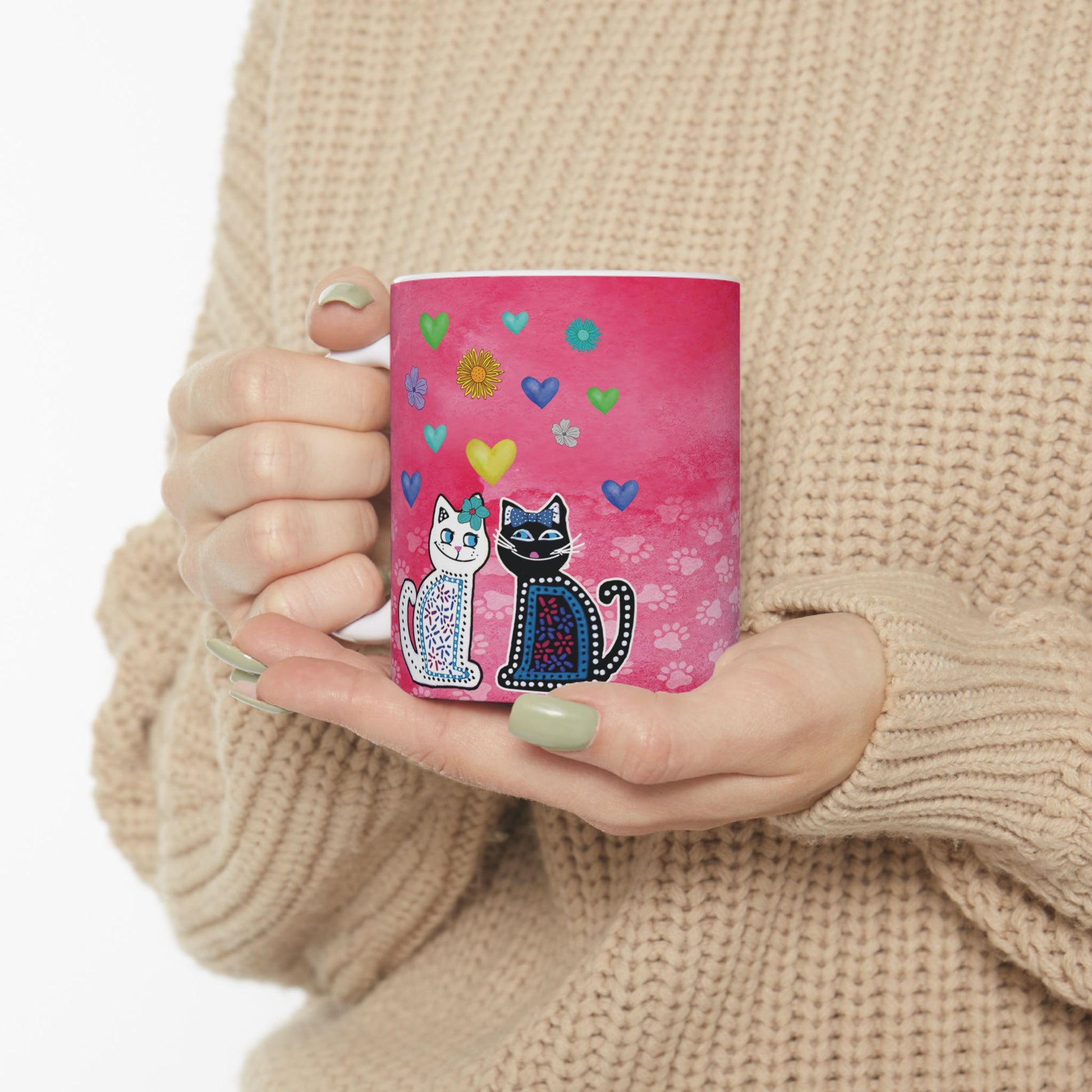 Mug with two cats and colorful hearts and flowers design on a pink background.