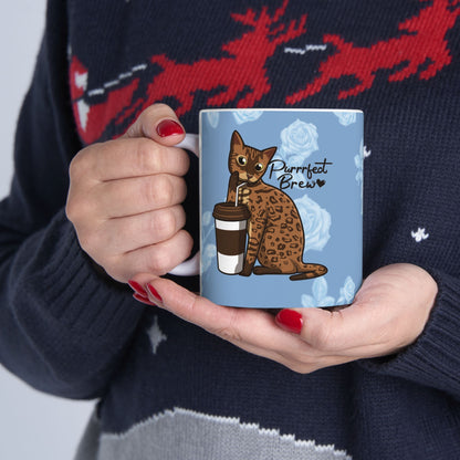 Mug with a Bengal cat drinking from a coffee cup and 'Purrrfect Brew' text on a blue floral patterned background.