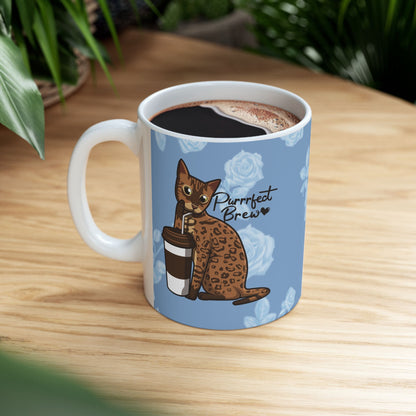 Mug with a Bengal cat drinking from a coffee cup and 'Purrrfect Brew' text on a blue floral patterned background.