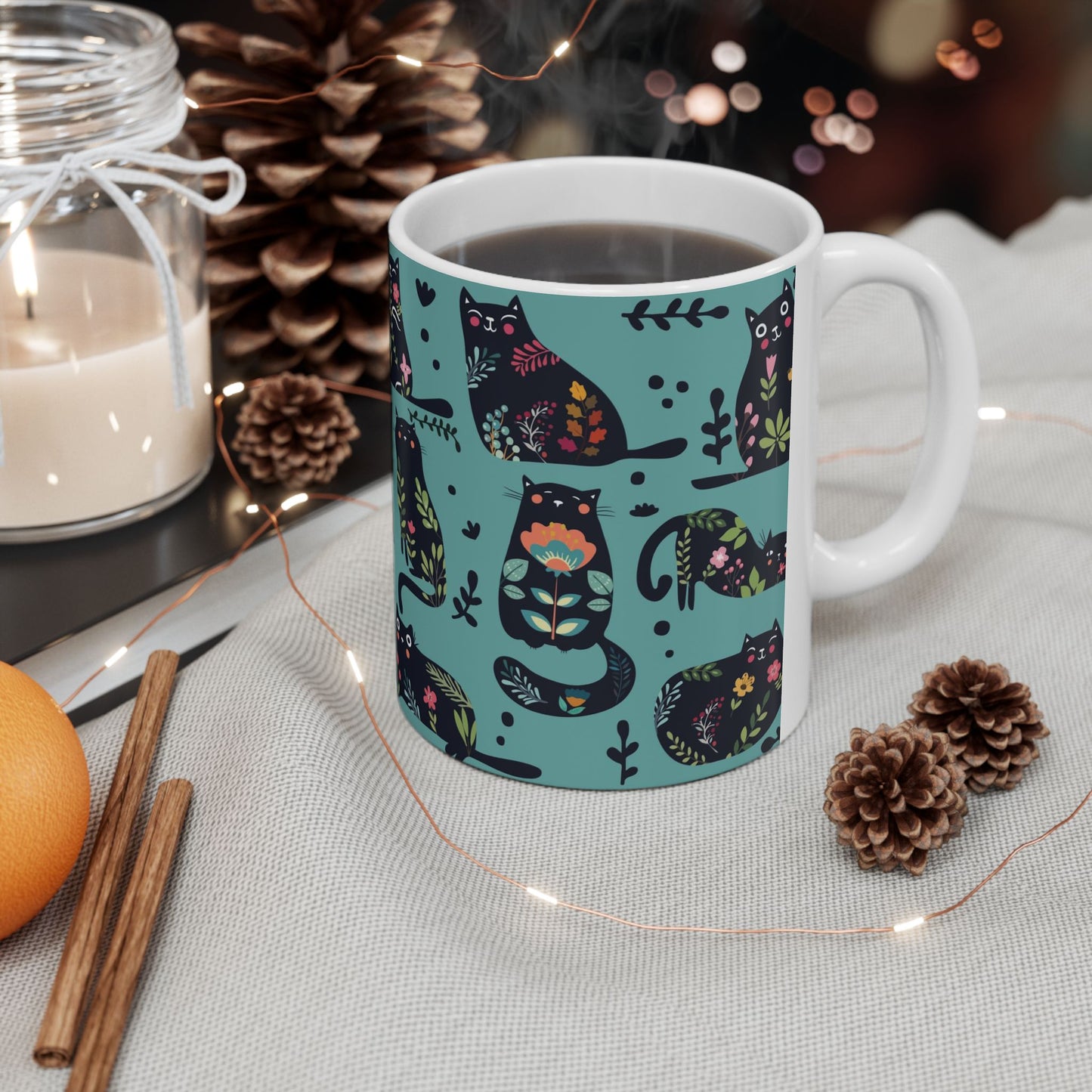 Mug with black cats and floral pattern on a blue background.