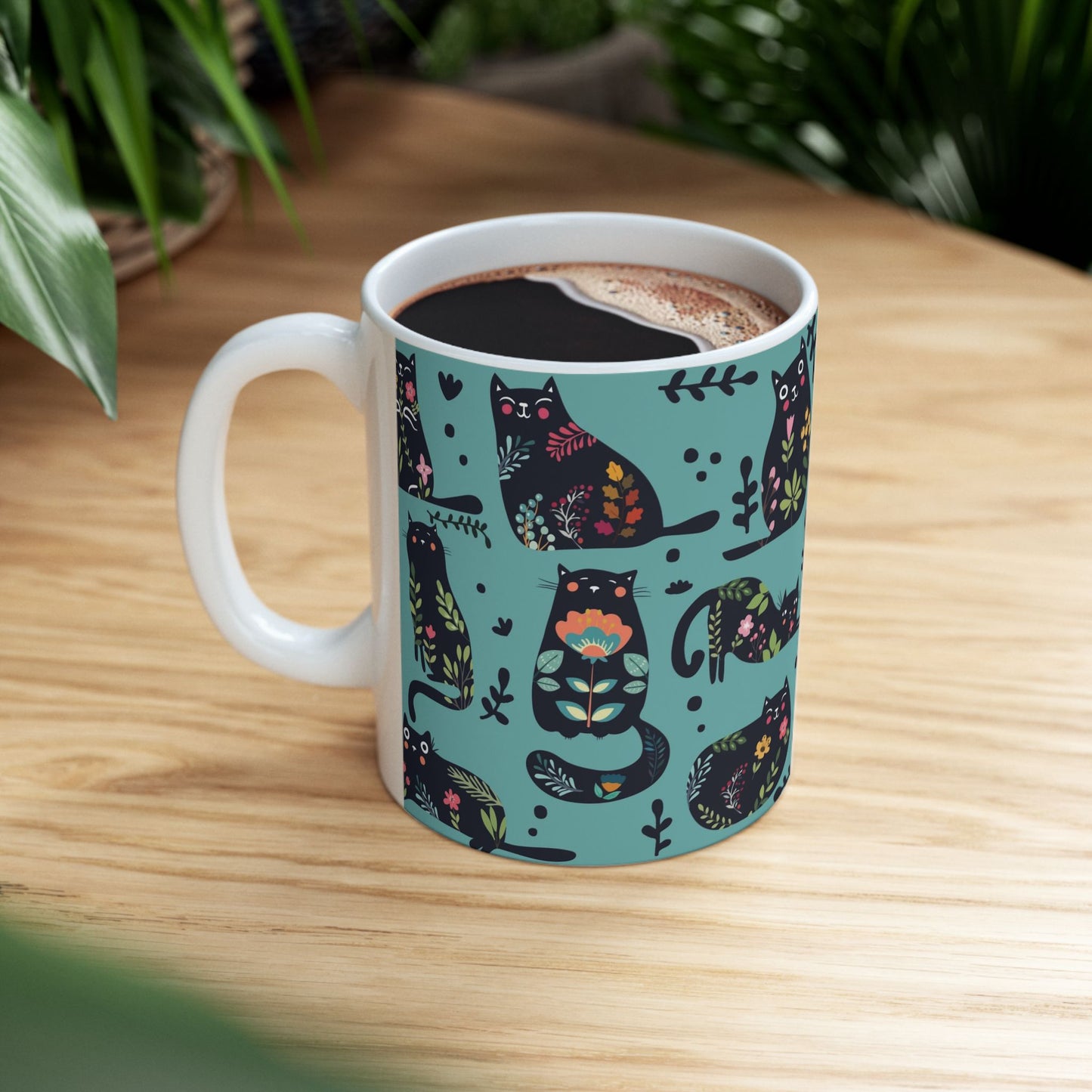 Mug with black cats and floral pattern on a blue background.