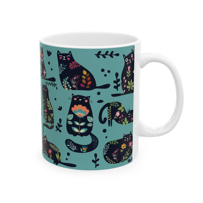 Mug with black cats and floral pattern on a blue background.