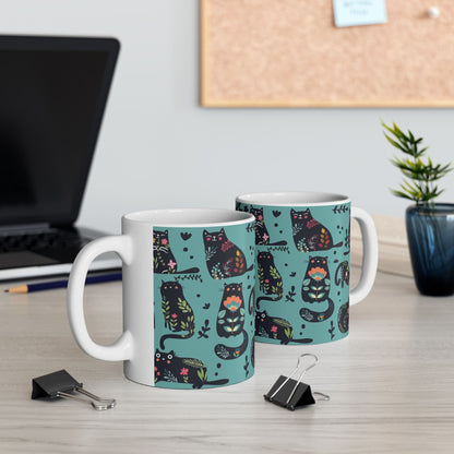 Mug with black cats and floral pattern on a blue background.