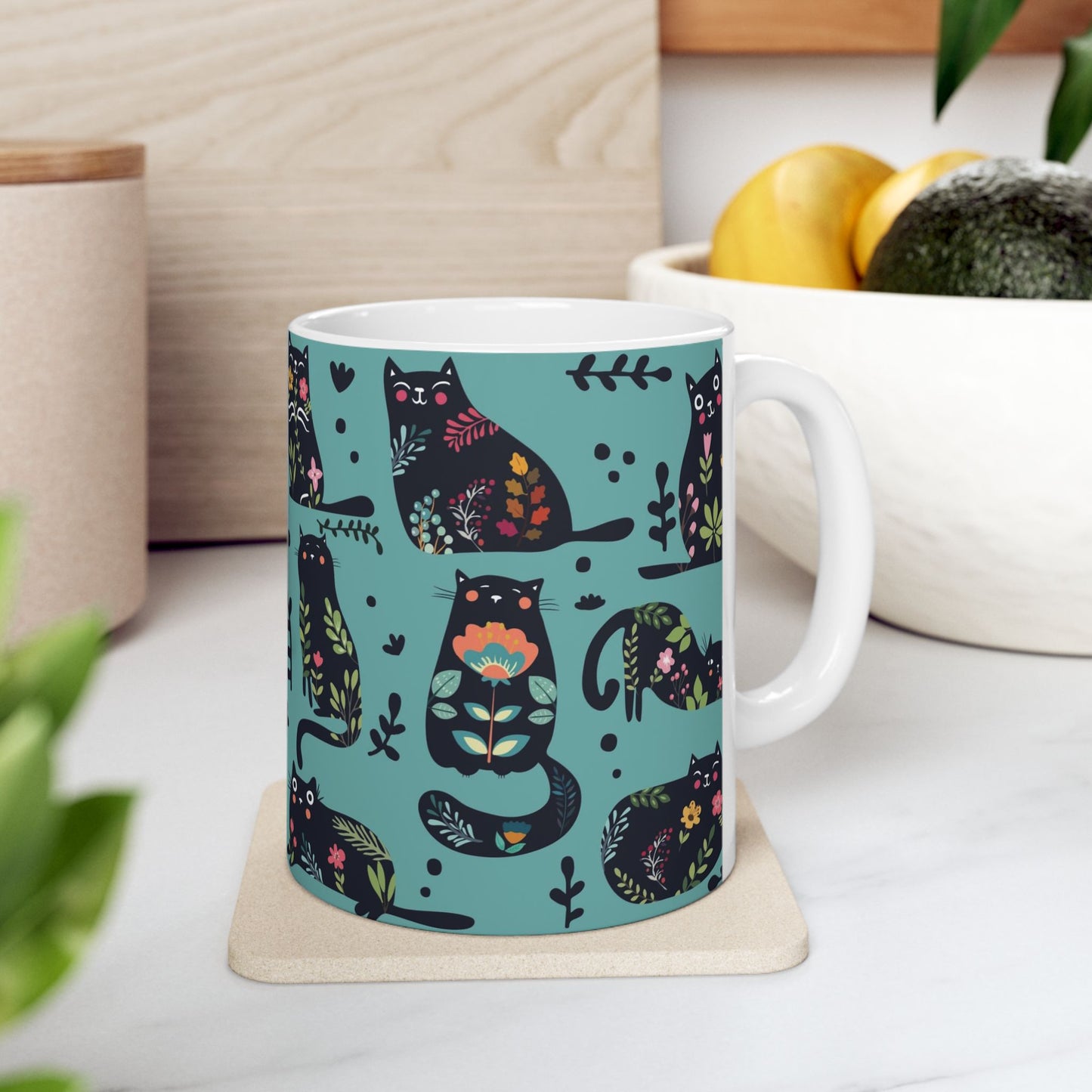 Mug with black cats and floral pattern on a blue background.