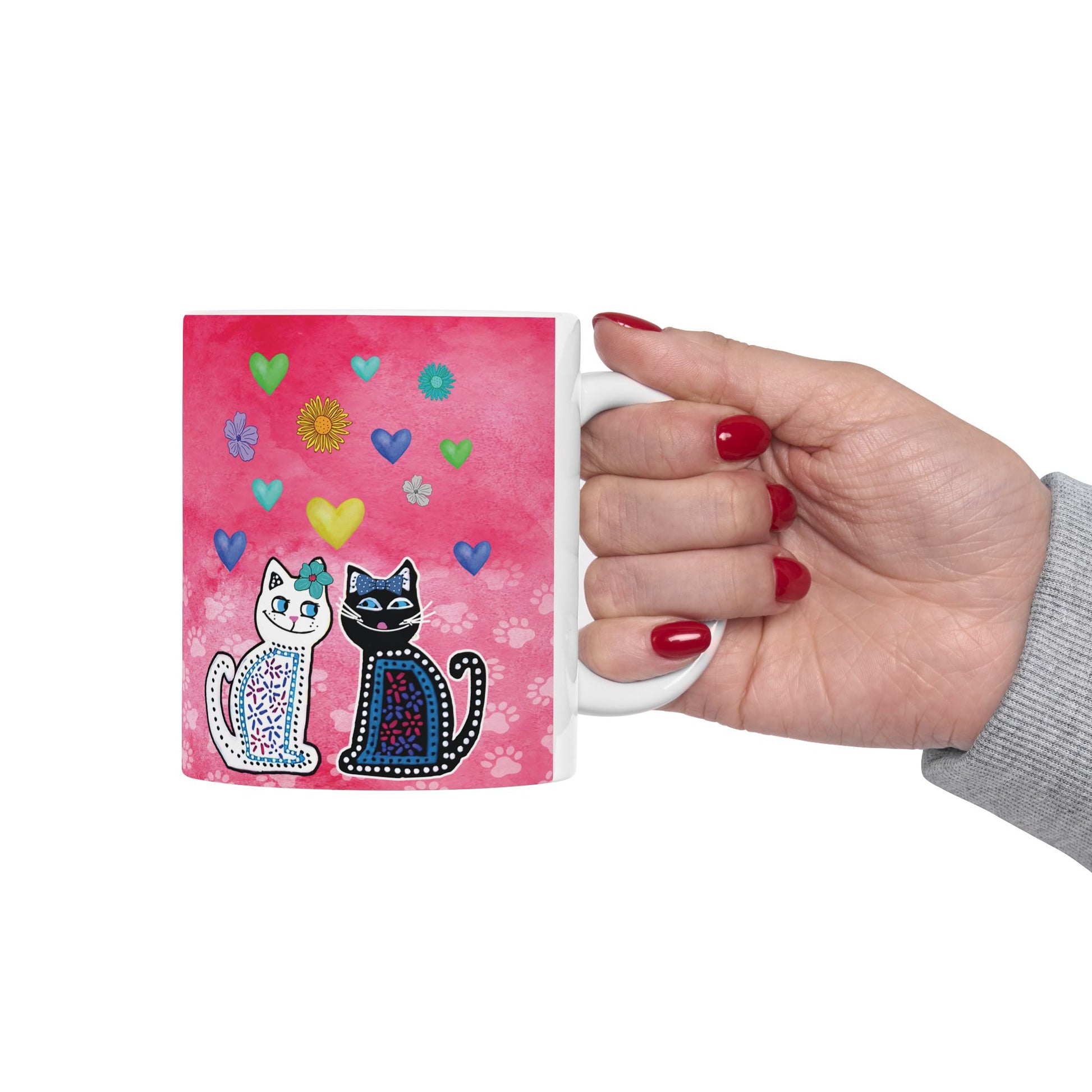 Mug with two cats and colorful hearts and flowers design on a pink background.