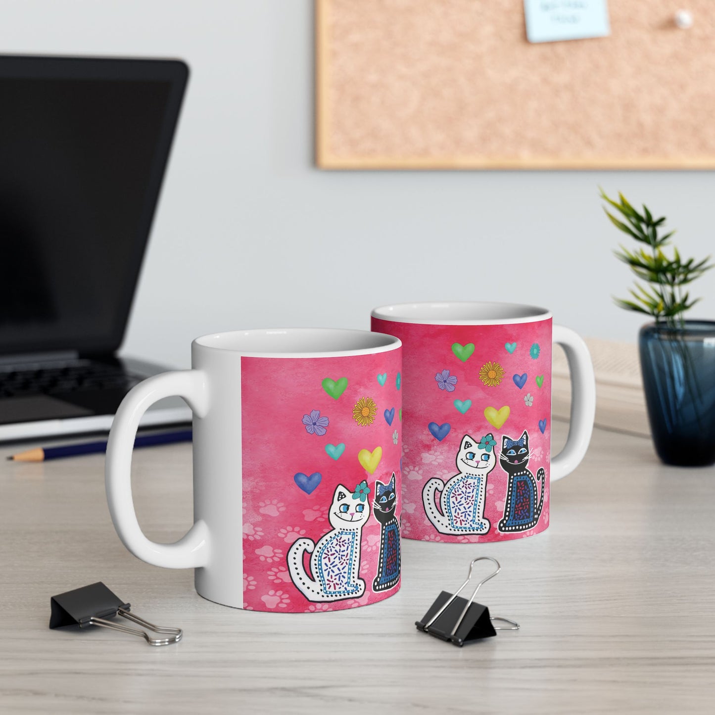 Mug with two cats and colorful hearts and flowers design on a pink background.