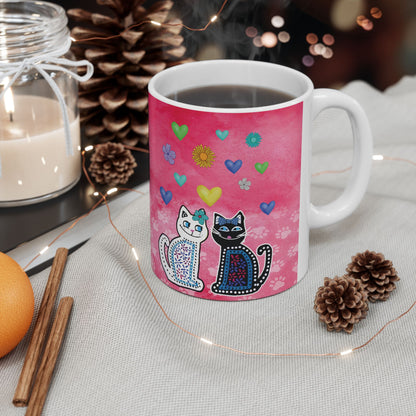 Mug with two cats and colorful hearts and flowers design on a pink background.