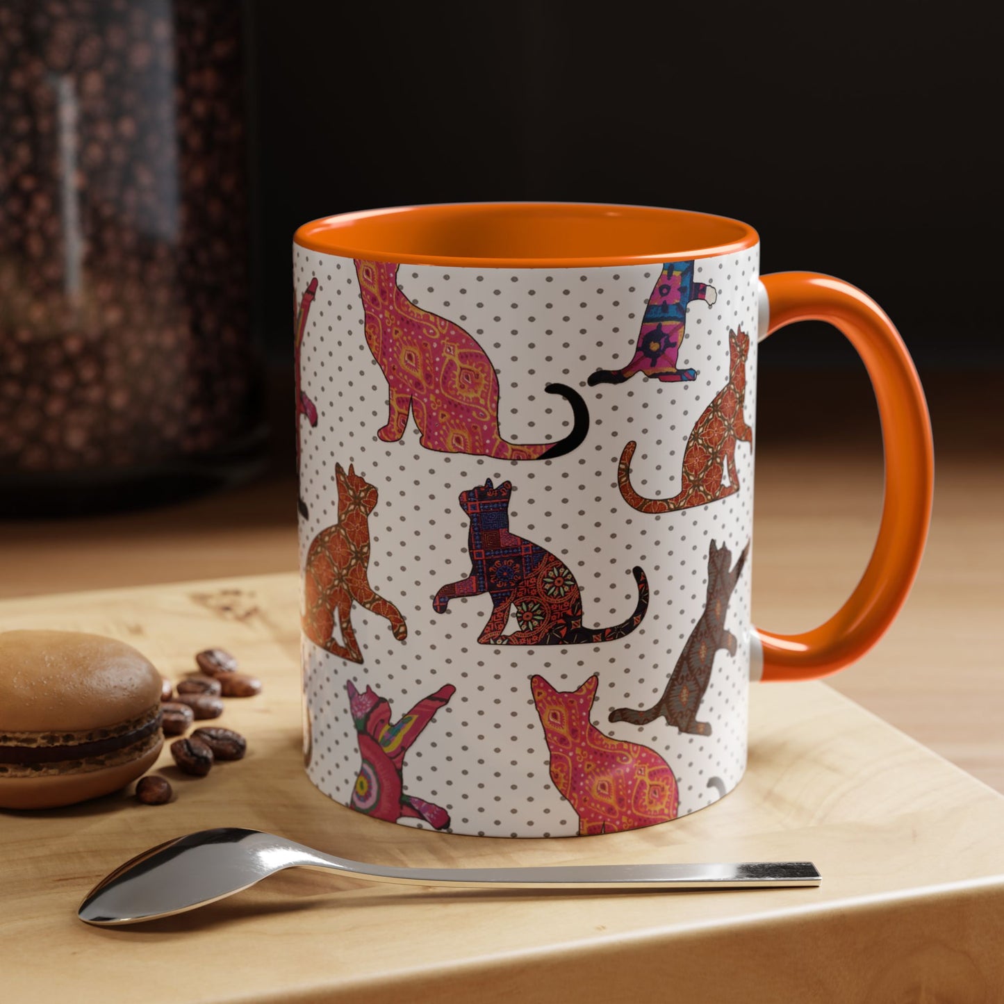 Orange mug with colorful cat silhouette pattern.