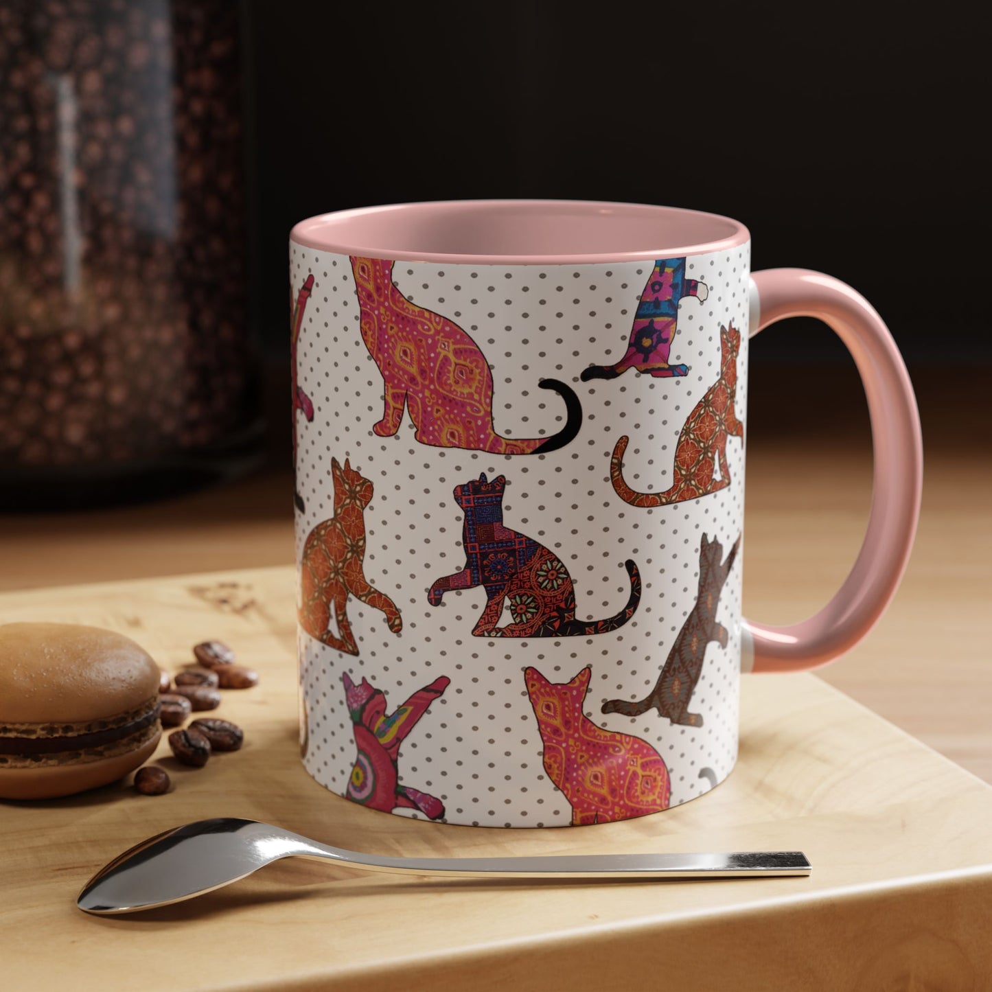 Pink mug with colorful cat silhouette pattern.