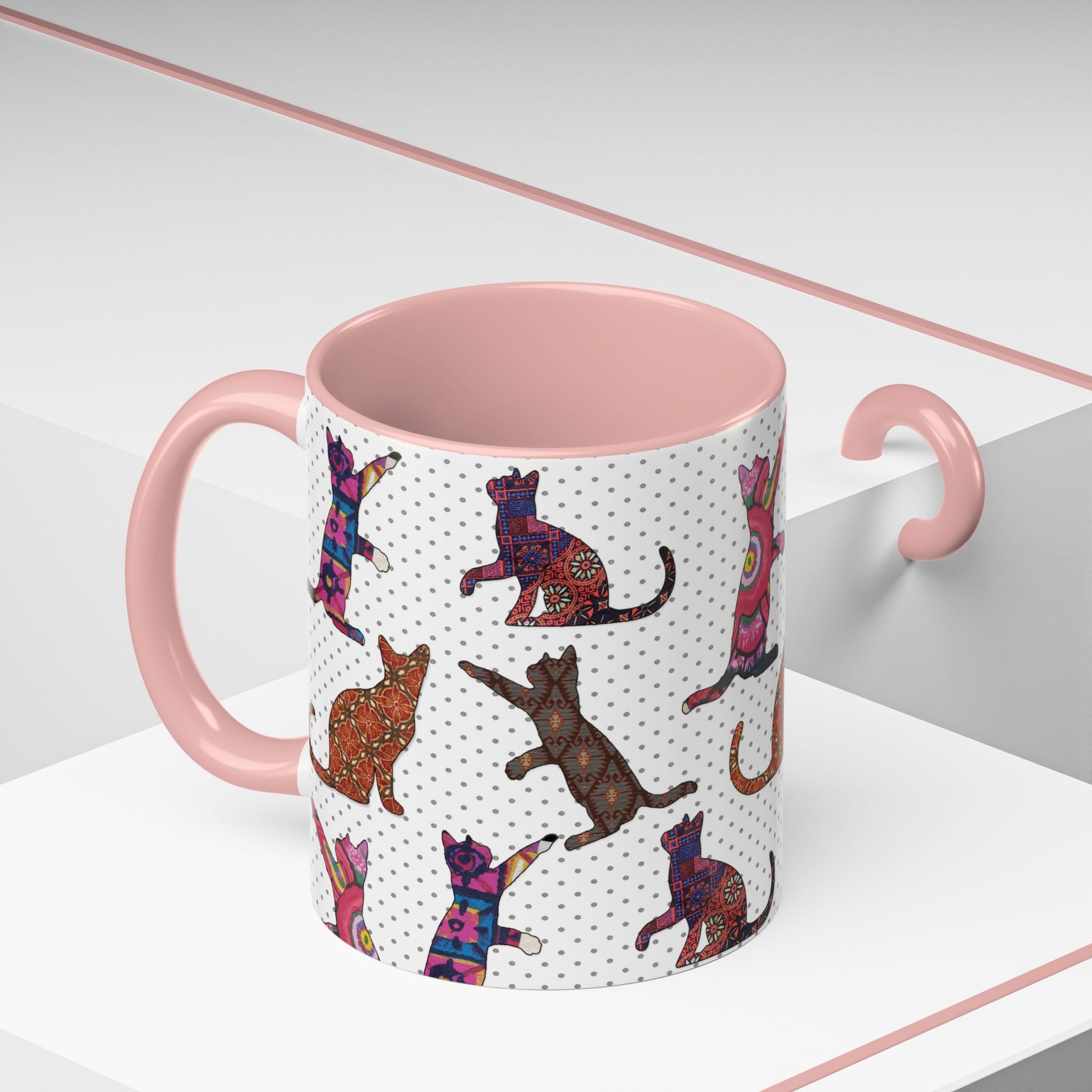 Pink mug with colorful cat silhouette pattern.