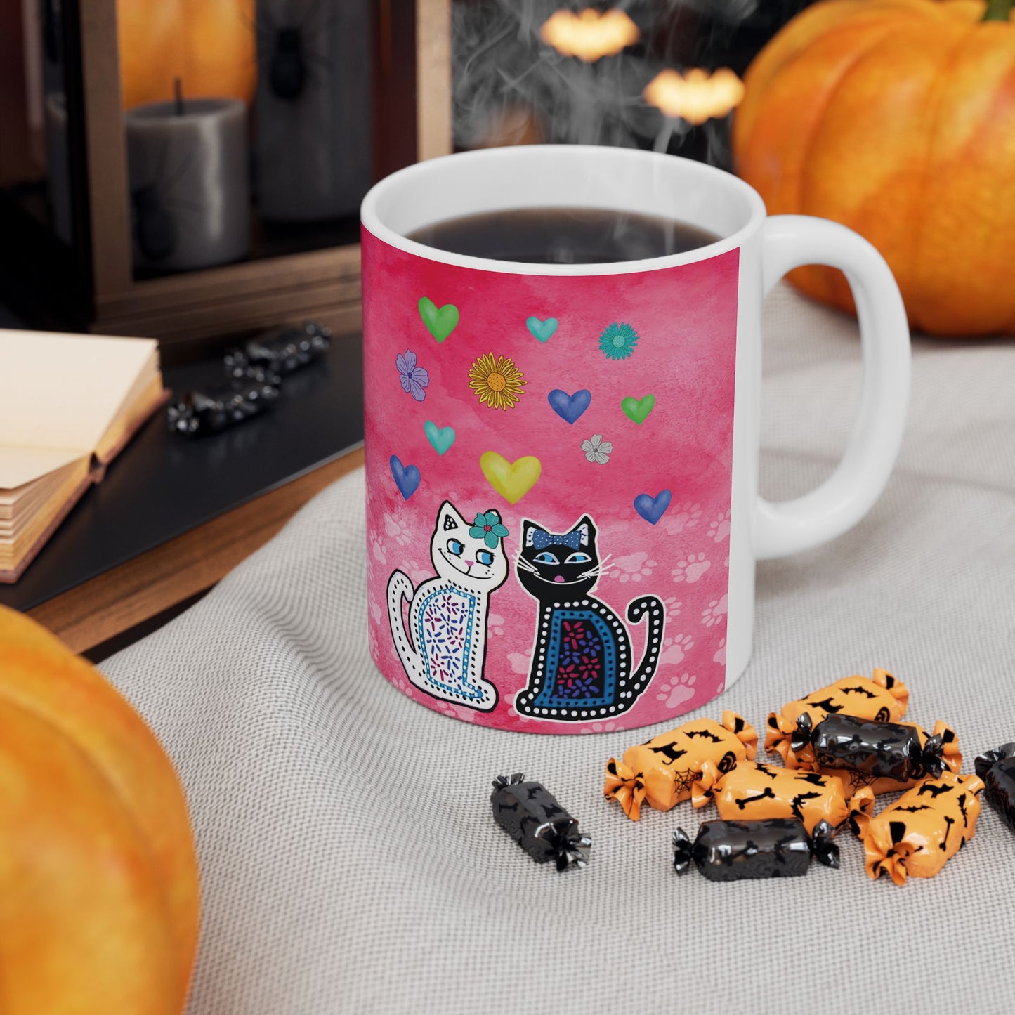 Mug with two cats and colorful hearts and flowers design on a pink background.