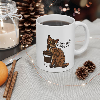 White mug with illustration of a Bengal Cat posing with a coffee cup and text 'Purrrfect Brew.'  