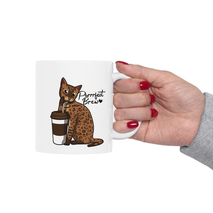 White mug with illustration of a Bengal Cat posing with a coffee cup and text 'Purrrfect Brew.'  