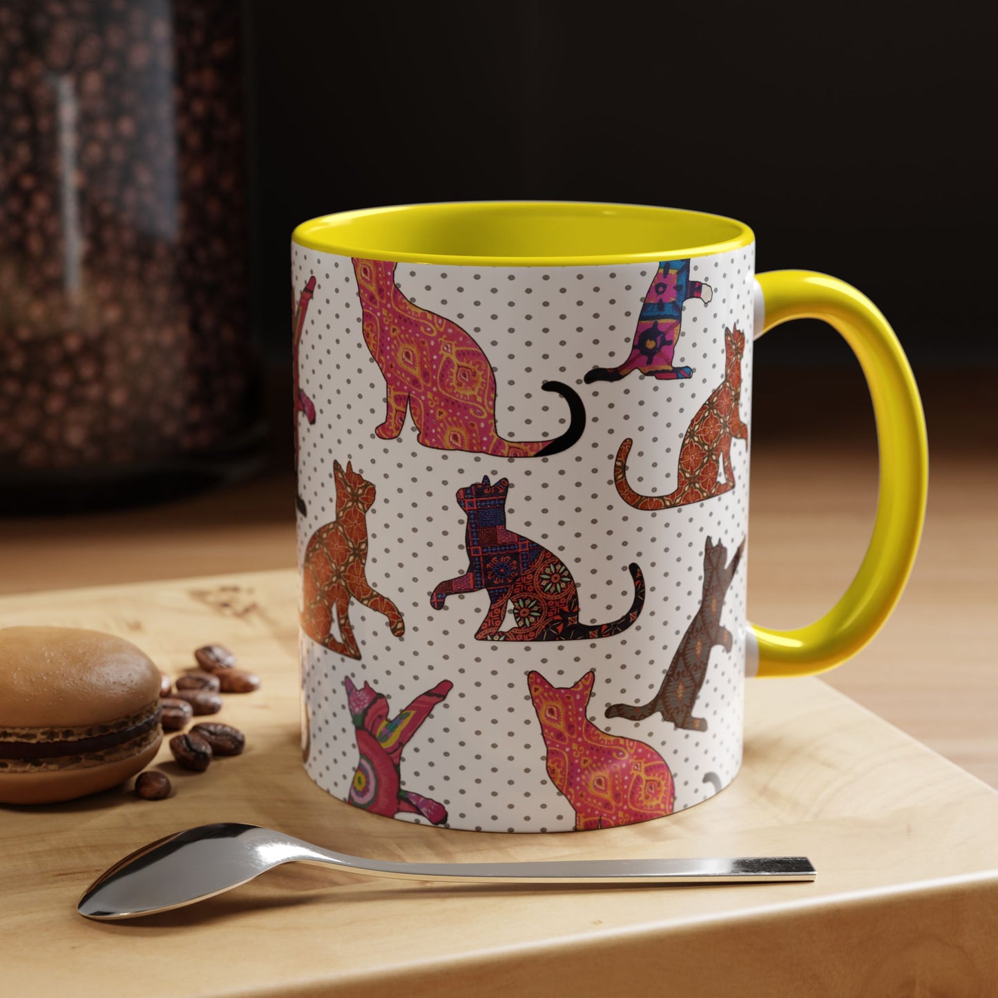 Yellow mug with colorful cat silhouette pattern.
