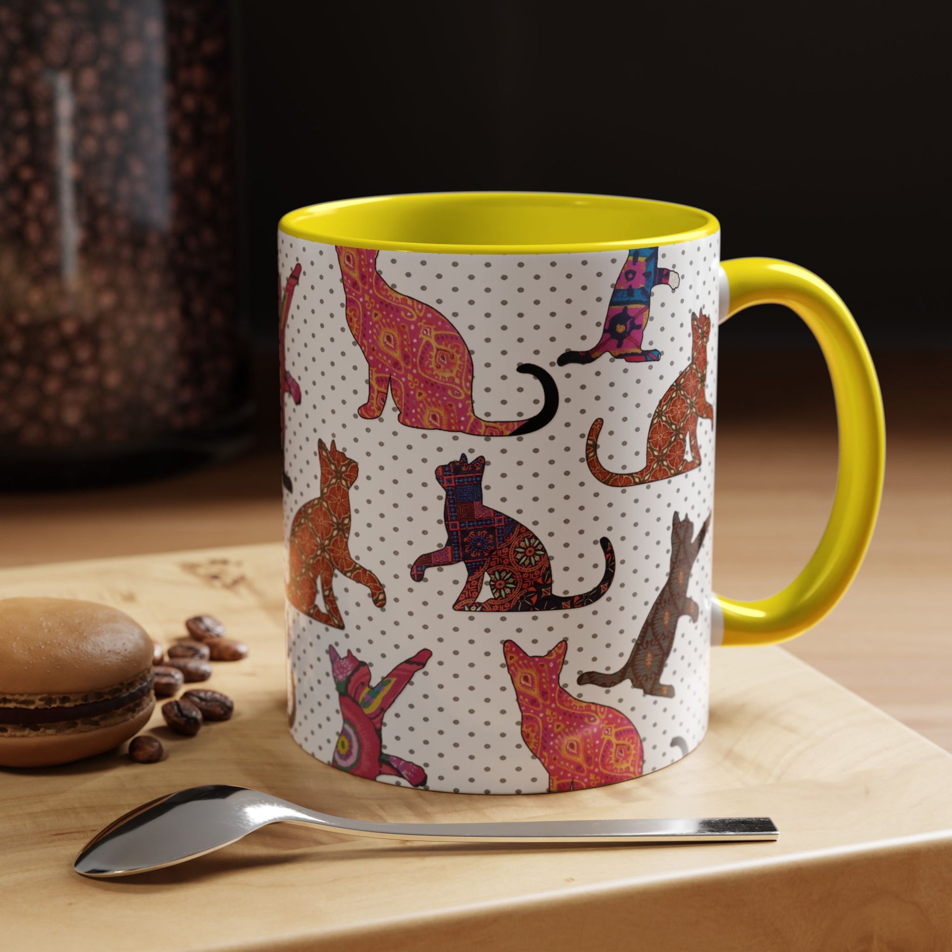 Yellow mug with colorful cat silhouette pattern.